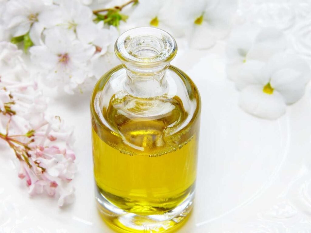 How is Oud Oil Extracted and Made? Golden oud oil in a glass bottle surrounded by delicate white flowers